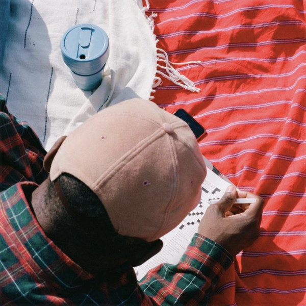 Man doing crossword puzzle with steel stojo cup